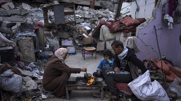 Members of the Al-Rabaya family break their fast during the Muslim holy month of Ramadan outside their destroyed home by the Israeli airstrikes in Rafah, Gaza Strip, Monday, March 18, 2024. - Sputnik Afrique
