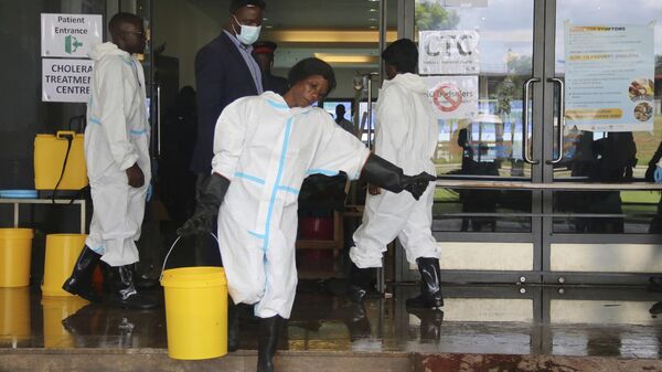 A worker carries a bucketfull of disinfectant at a cholera treatment centre, in Lusaka, Zambia - Sputnik Africa