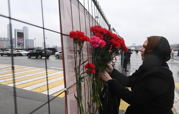 People carry flowers to the building of the Crocus City Hall concert venue, where the shooting took place and the fire started. - Sputnik Africa