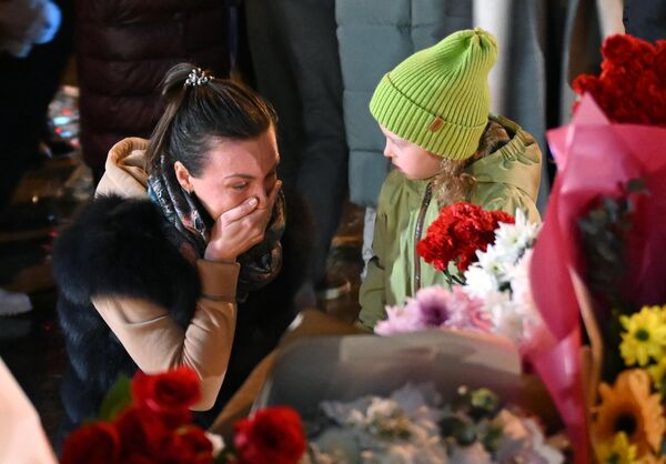 A woman and a little girl laying flowers at a memorial near Crocus City Hall.According to investigators, terrorists killed entire families with children who came to the Crocus for the concert. - Sputnik Africa