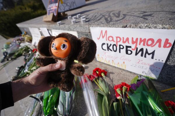 The citizens of Mariupol have erected a monument to the memory of the victims of the terrorist attack. The person in the photo is holding Cheburashka, a popular Russian character. - Sputnik Africa