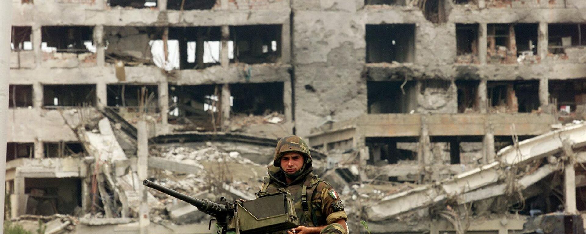 An Italian KFOR soldier mans a machine gun atop an armored vehicle in front of the NATO destroyed Serbian police headquarters at the entrance to the western Kosovo town of Djakovica 09 July, 1999. - Sputnik Africa, 1920, 24.03.2024