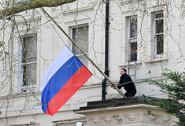 A person adjusts the Russian national flag to fly at half-mast on the building of the Russian Embassy in London.  - Sputnik Africa