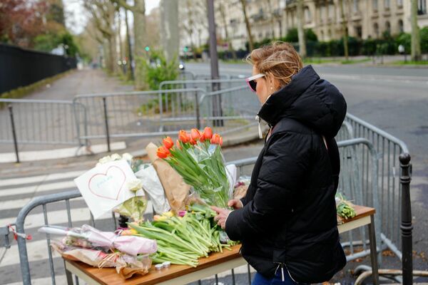 A woman holds a bunch of flowers at a makeshift memorial in front of Russia&#x27;s Embassy in Paris.  - Sputnik Africa