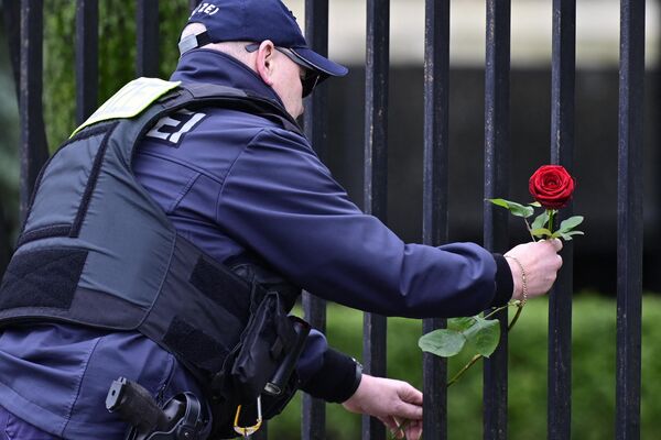 A police officer lays flower outside the Russian Embassy in Berlin.  - Sputnik Africa