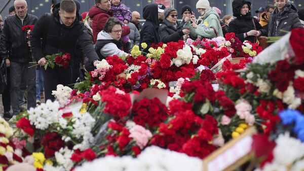 People place flowers and toys at the fence next to the Crocus City Hall, on the western edge of Moscow, Russia, Sunday, March 24, 2024. \ - Sputnik Africa