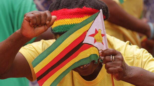 A woman celebrates while holding the Zimbabwean flag, as Zimbabwean President Robert Mugabe arrives for celebrations to mark 35 years of Independence at the National Sports stadium in Harare, Saturday, April, 18, 2015.  - Sputnik Afrique