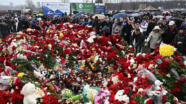People lay flowers at a makeshift memorial in memory of the victims of the March 22 terrorist attack on the Crocus City Hall concert venue near Moscow, in Moscow Region, Russia. Russian President Vladimir Putin declared March 24 a day of national mourning in Russia for those killed in the terrorist attack. - Sputnik Afrique