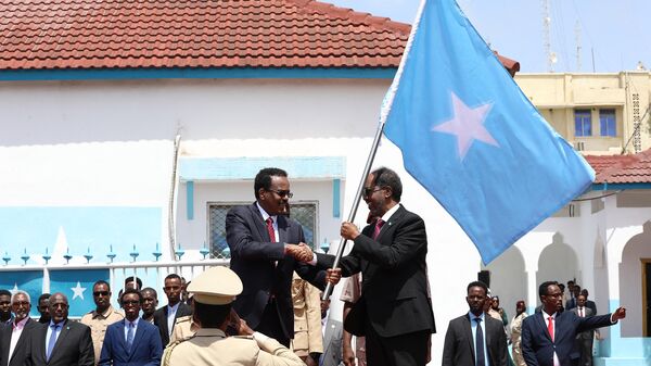 Outgoing Somalia President Mohamed Abdullahi Mohamed (C-L), also known as Farmaajo, presents the Somali flag to newly elected President Hassan Sheikh Mohamud (C-R), during the handover ceremony at the Mogadishu palace on May 23, 2022.  - Sputnik Afrique