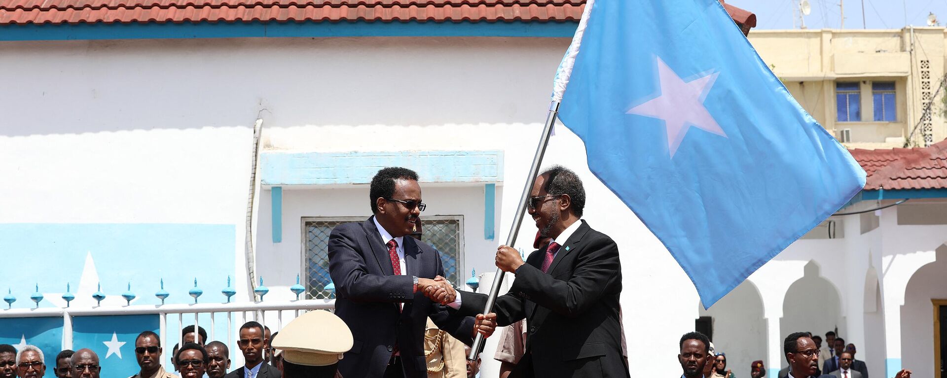 Outgoing Somalia President Mohamed Abdullahi Mohamed (C-L), also known as Farmaajo, presents the Somali flag to newly elected President Hassan Sheikh Mohamud (C-R), during the handover ceremony at the Mogadishu palace on May 23, 2022.  - Sputnik Africa, 1920, 31.03.2024