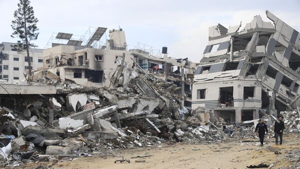 Palestinians walk past the building destroyed in the Israeli Bombardment of the Gaza Strip in Gaza City on Wednesday, Jan. 3, 2024 - Sputnik Africa