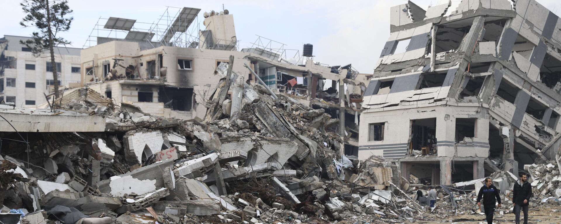 Palestinians walk past the building destroyed in the Israeli Bombardment of the Gaza Strip in Gaza City on Wednesday, Jan. 3, 2024 - Sputnik Africa, 1920, 02.05.2024