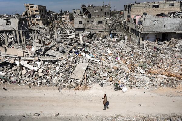 A man walks past the rubble of a destroyed building in Khan Yunis on April 7, 2024 after Israel pulled its ground forces out of the southern Gaza Strip. - Sputnik Africa