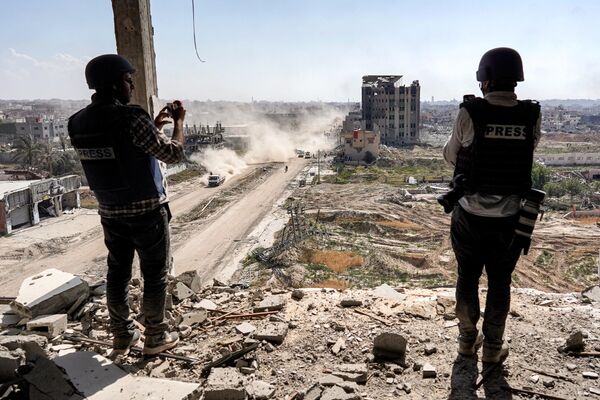 Journalists film from atop a damaged building facing the ravaged building of Al-Salam hospital in Khan Yunis on April 7, 2024 after Israel pulled its ground forces out of the southern Gaza Strip. - Sputnik Africa