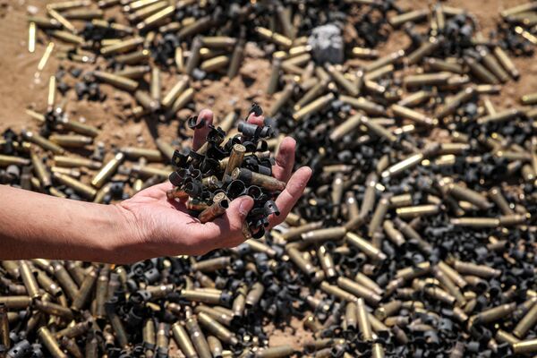A person holds a handful of spent bullet casings above a bigger pile in Khan Yunis on April 7, 2024 after Israel pulled its ground forces out of the southern Gaza Strip. - Sputnik Africa