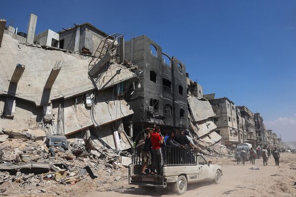 Palestinians use a road in front of damaged buildings in Khan Yunis on April 7, 2024 after Israel pulled troops out of the southern Gaza Strip. - Sputnik Africa