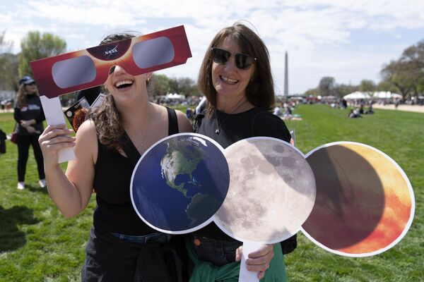Mackenzie Trumbull, left, and Kathy Trumbull gather to watch as the moon partially covers the sun during a total solar eclipse as seen from the National Mall in Washington, Monday, April 8, 2024.  - Sputnik Africa