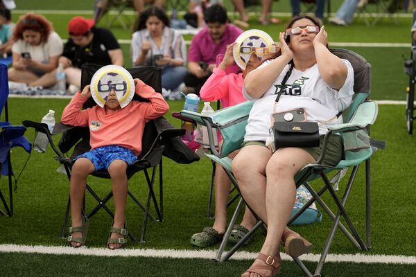 Karine Rodriquez, right, sits with her son Yurem, left, and daughter Aranza, center, as the moon partially covers the sun during a total solar eclipse, as seen from Eagle Pass, Texas, Monday, April 8, 2024.  - Sputnik Africa