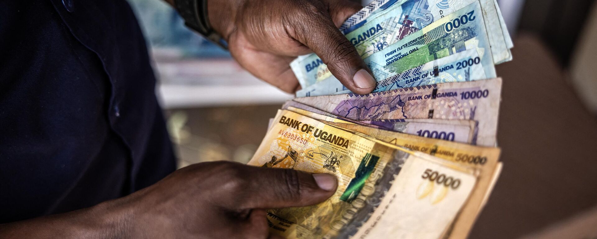 A man working for a forex bureau displays some Ugandan shilling notes for a costumer in downtown Kampala on January 20, 2024 - Sputnik Africa, 1920, 16.04.2024