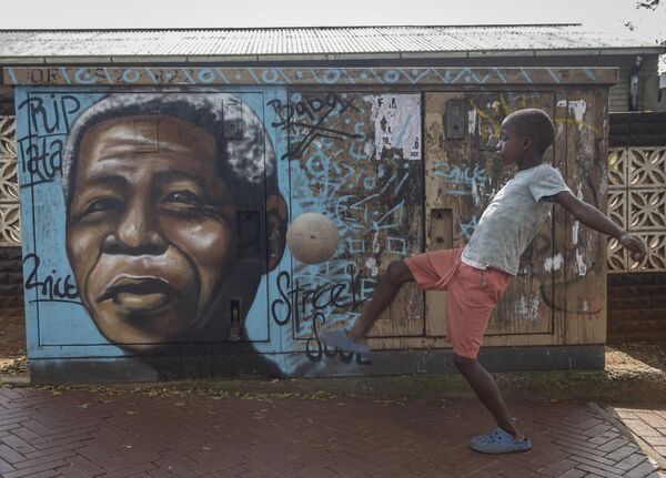 Мальчик играет в мяч возле мурала с изображением Нельсона Манделы в Соуэто, Южная Африка - Sputnik Africa
