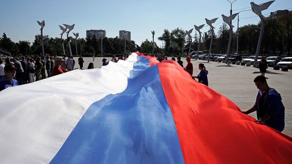 People hold a giant Russian flag during celebrations of the Russia's National Flag Day - Sputnik Africa
