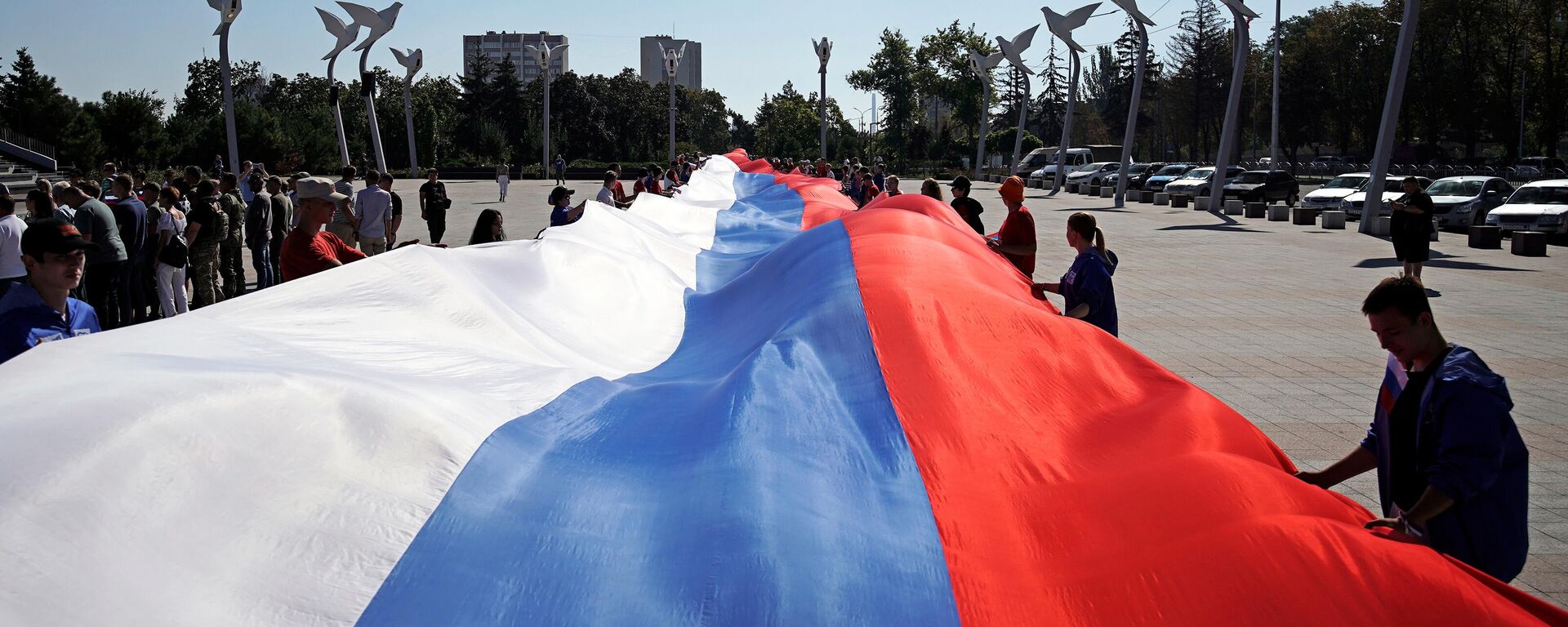 People hold a giant Russian flag during celebrations of the Russia's National Flag Day - Sputnik Africa, 1920, 27.04.2024