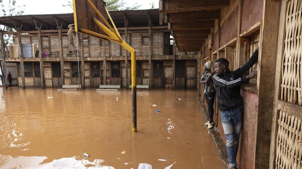 Les habitants du bidonville de Mathare traverse un terrain d'école inondé, à la suite de fortes pluies qui se sont abattues sur  Nairobi, le 24 avril 2024 - Sputnik Afrique