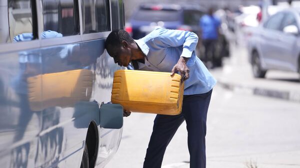A man puts fuel inside a company bus near a petrol station in Lagos, Nigeria, Tuesday April 30, 2024.  - Sputnik Africa