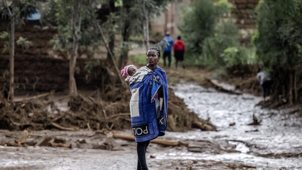 Une femme portant son bébé, après des pluies torrentielles et des crues au Kenya, fin avril 2024 - Sputnik Afrique