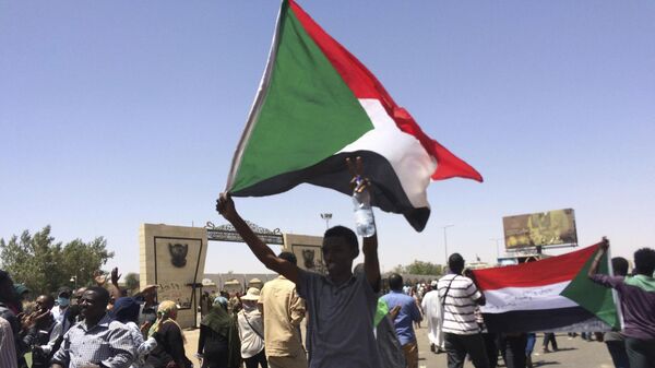 Protesters display Sudanese flags at a rally in front of the military headquarters in the capital Khartoum, Sudan, Monday, April 8, 2019.  - Sputnik Africa