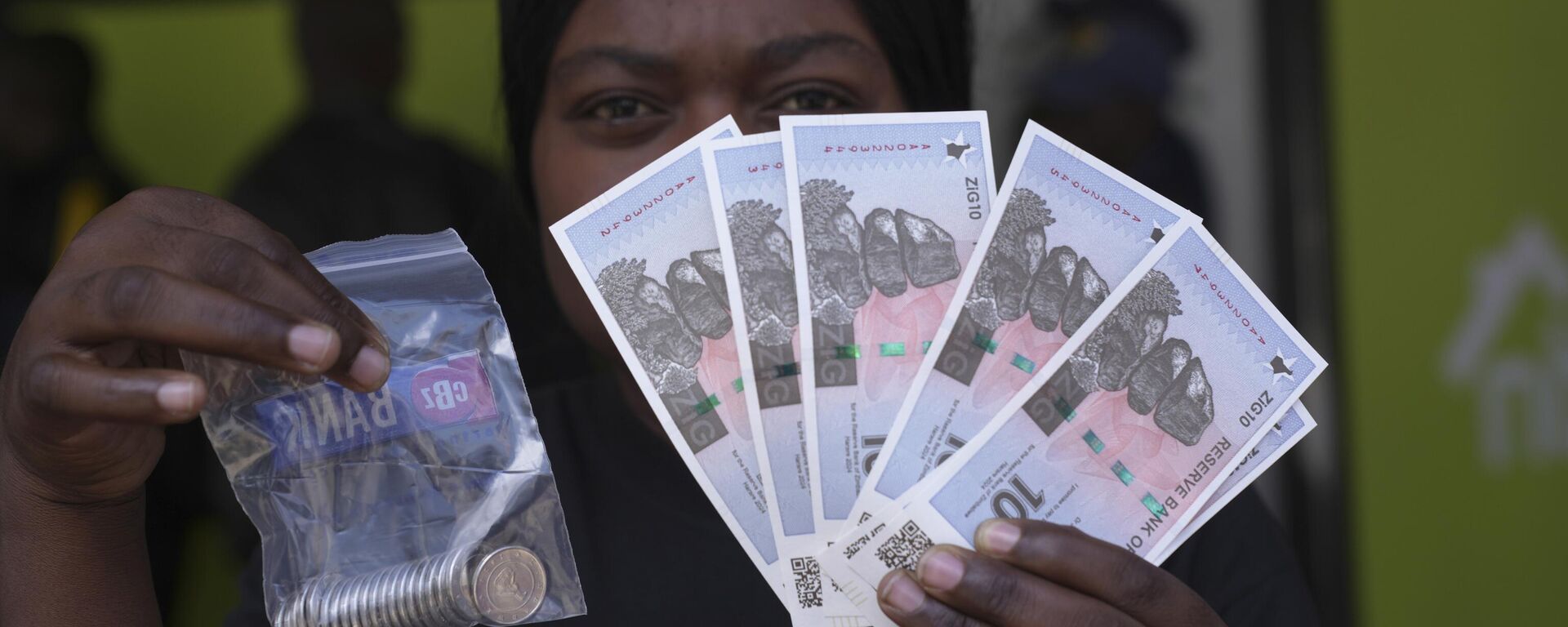 A woman holds the new Zimbabwean banknotes and coins called the ZiG, in the streets of Harare, Zimbabwe, Tuesday, April 30, 2024. - Sputnik Africa, 1920, 07.05.2024