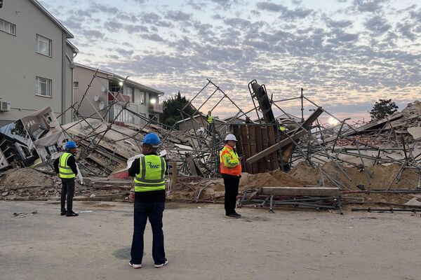 Officials are seen at the scene of a collapsed building in George on May 7, 2024. - Sputnik Africa