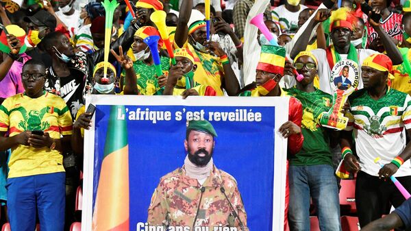 Les supporters du Mali tiennent un portrait du chef de la junte malienne, le colonel Assimi Goita, avant le huitième de finale de la Coupe d'Afrique des Nations (CAN) 2021 entre le Mali et la Guinée équatoriale au stade omnisport de Limbé, à Limbé, le 26 janvier 2022.  - Sputnik Afrique