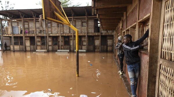 Residents of Mathare slum use the wall to cross a flooded school field, following heavy down pour in the capital, Nairobi on April 24, 2024. - Sputnik Africa