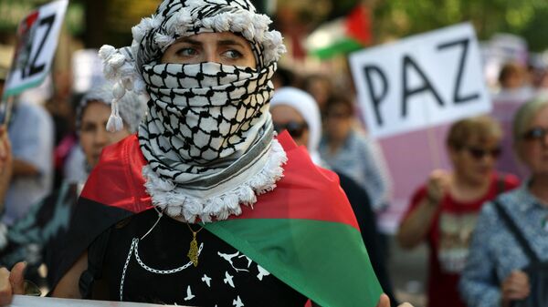 A woman wrapped in a Palestinian flag and wearing a keffiyeh takes part in a demonstration in support of the Palestinian people from the Gaza Strip, in Madrid on May 11, 2024.  - Sputnik Africa
