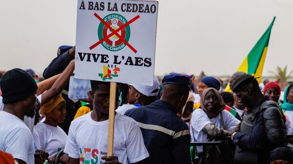 A supporter of the Alliance Of Sahel States (ASS) holds a placard reading 'down with ECOWAS, long live ASS' during a rally to celebrate Mali, Burkina Faso and Niger leaving the Economic Community of West African States (ECOWAS) in Bamako on February 1, 2024.  - Sputnik Africa