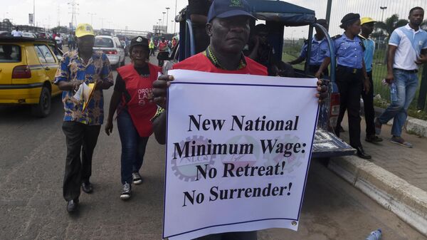 A worker holding a printed message takes part in a march to protest against the government's failure to agree on a new minimum wage during a rally in Lagos, on October 30, 2018. - Sputnik Africa