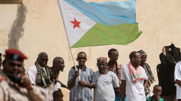 People hold Djiboutian national flag as they wait for the arrival of Djibouti's President Ismail Omar Guellehas before the launching ceremony of new 1000-unit housing construction project in Djibouti, on July 4, 2018.  - Sputnik Africa