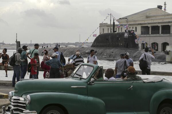 A convertible car drives by as people watch the anticipated visit of the Russian ships. - Sputnik Africa
