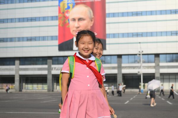Schoolgirls near a building with a banner with a portrait of Russian President Vladimir Putin in Pyongyang. - Sputnik Africa