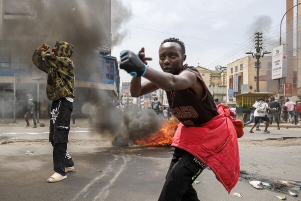 Protesters gesture at Kenya anti-riot police around a burning barricade during an anti-government demonstration called following nationwide deadly protests over tax hikes and a controversial now-withdrawn tax bill in downtown Nairobi, on July 2, 2024. - Sputnik Africa