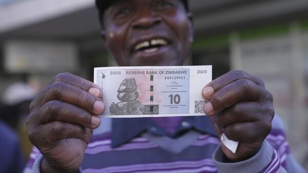 A man smiles while holding the new Zimbabwean banknote, called the ZiG, in the streets of Harare, Zimbabwe, Tuesday, April 30, 2024. - Sputnik Africa