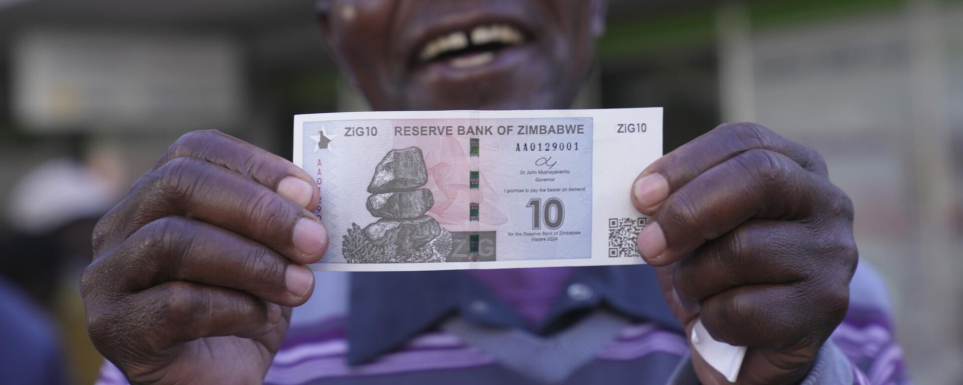 A man smiles while holding the new Zimbabwean banknote, called the ZiG, in the streets of Harare, Zimbabwe, Tuesday, April 30, 2024. - Sputnik Africa, 1920, 05.07.2024