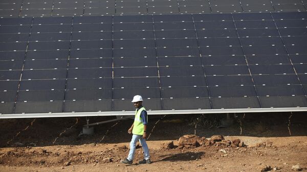 An official walks past solar panels installed at  the Pavagada Solar Park 175 Kilometers (109 miles) north of Bangalore, India, Thursday, March 1, 2018.  - Sputnik Africa