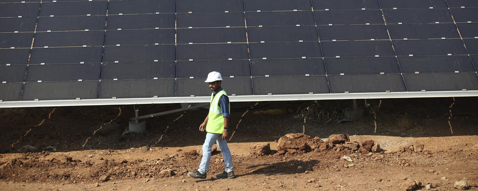 An official walks past solar panels installed at  the Pavagada Solar Park 175 Kilometers (109 miles) north of Bangalore, India, Thursday, March 1, 2018.  - Sputnik Africa, 1920, 09.07.2024