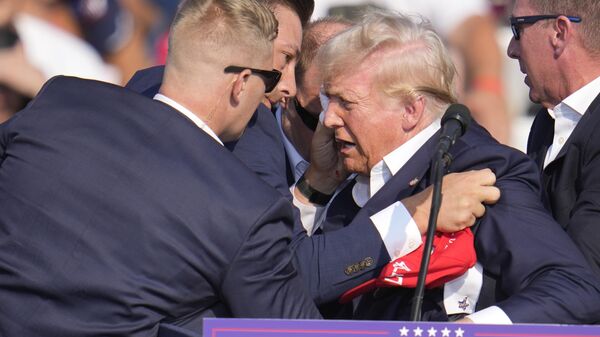 Republican presidential candidate former President Donald Trump is helped off the stage by US Secret Service agents at a campaign event in Butler, Pa., on Saturday, July 13, 2024. - Sputnik Afrique