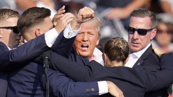Republican presidential candidate former President Donald Trump is helped off the stage by U.S. Secret Service agents at a campaign event in Butler, Pa., on Saturday, July 13, 2024.  - Sputnik Africa