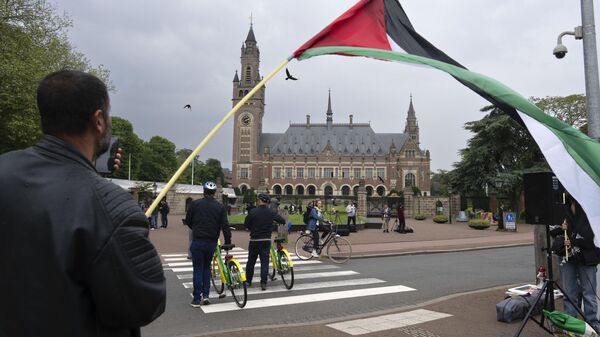 A lone demonstrator waves the Palestinian flag outside the Peace Palace, rear, housing the International Court of Justice, or World Court, in The Hague, Netherlands, Friday, May 24, 2024.  - Sputnik Africa