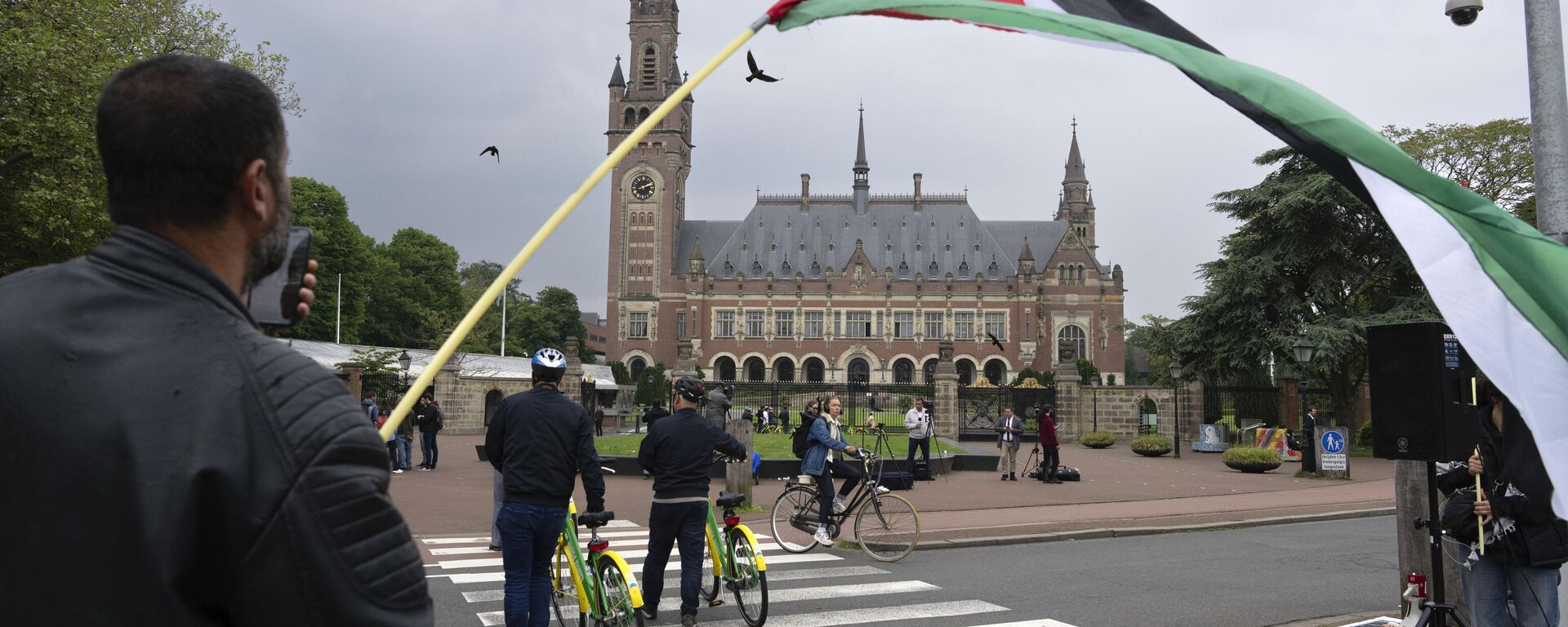 A lone demonstrator waves the Palestinian flag outside the Peace Palace, rear, housing the International Court of Justice, or World Court, in The Hague, Netherlands, Friday, May 24, 2024.  - Sputnik Africa, 1920, 20.07.2024