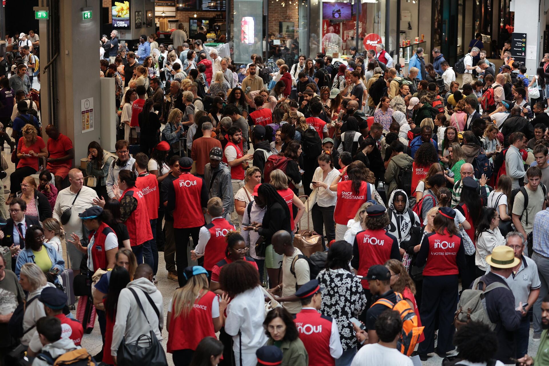 Employees of SNCF railway company speak to passengers waiting for their trains' departure at the Gare Montparnasse train station in Paris on July 26, 2024 as France's high-speed rail network was hit by malicious acts disrupting the transport system hours before the opening ceremony of the Paris 2024 Olympic Games. According to SNCF a massive attack on a large scale hit the TGV network and many routes will have to be cancelled. SNCF urged passengers to postpone their trips and stay away from train stations. - Sputnik Africa, 1920, 26.07.2024